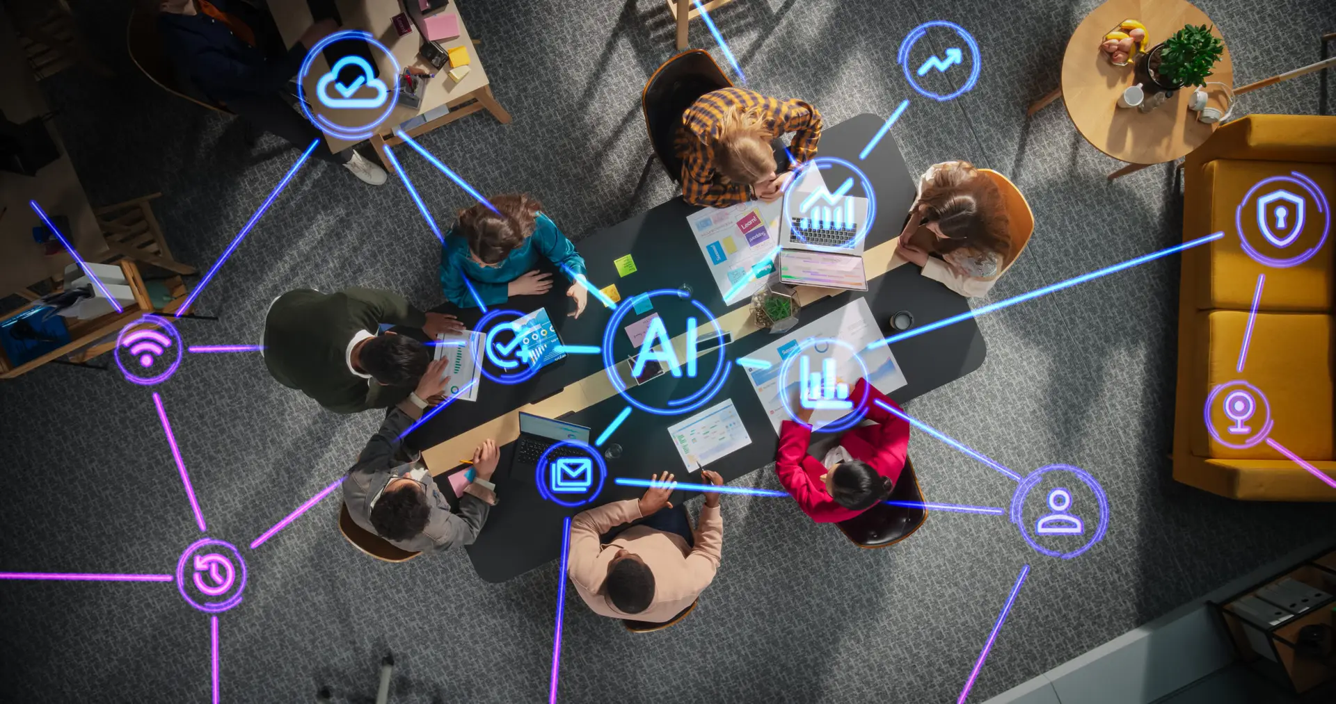 Overhead view of a diverse business team sitting around a conference table, overlaid with glowing digital network lines connecting a central AI node to cloud, security, email, and data icons.